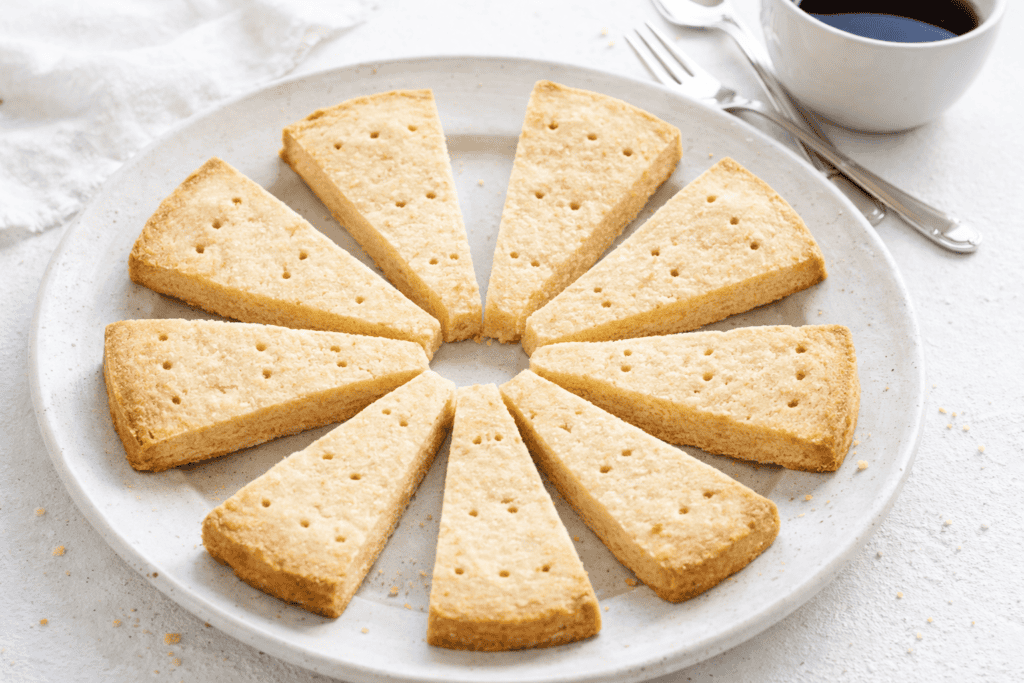 Sponge cake slices arranged in a circle on a white plate with a cup of coffee nearby.
