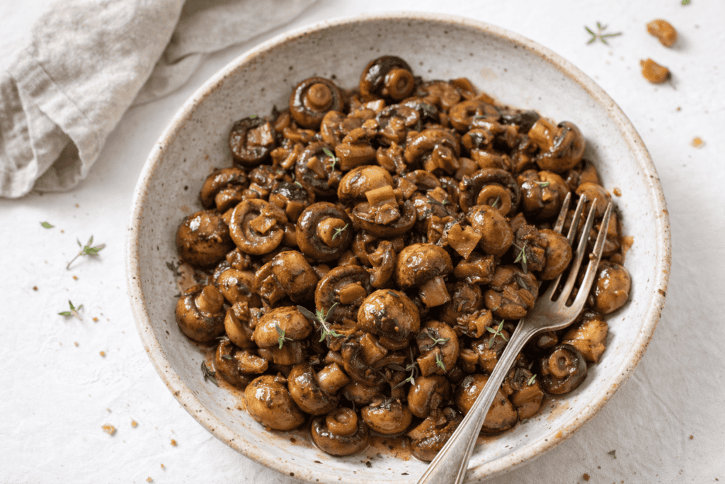 Delicious sautéed mushrooms garnished with herbs in a rustic bowl.