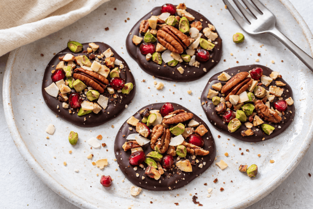 Delicious chocolate bark topped with pecans, pistachios, and dried cranberries, perfect for snacking.