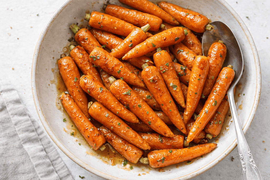 Sweet glazed carrots with herbs in a white bowl, ready to serve as a nutritious side dish.
