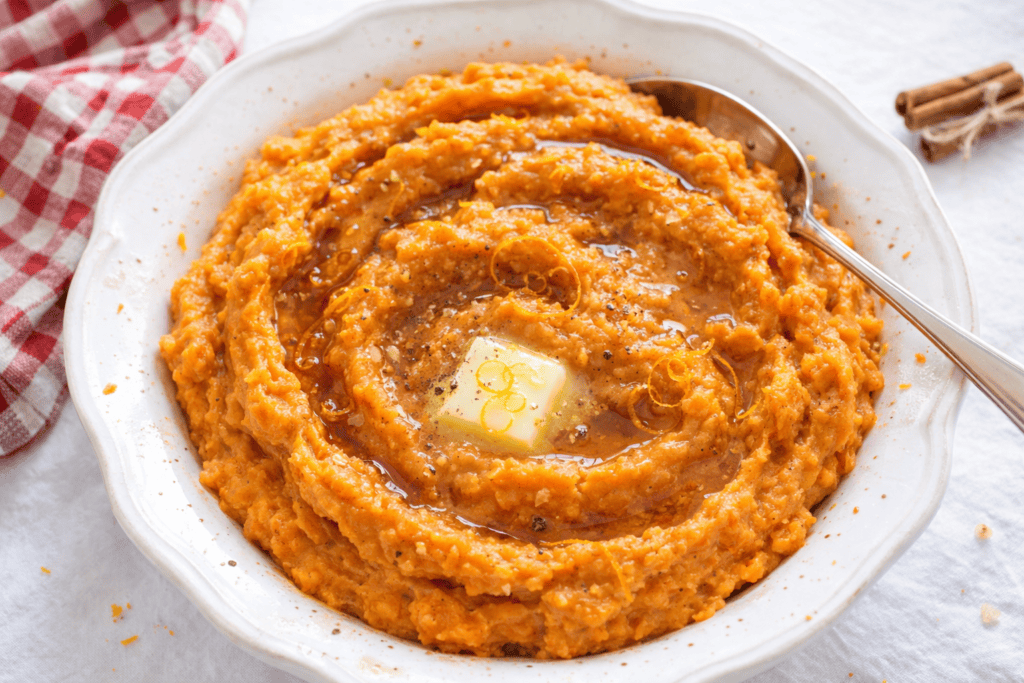 Delicious creamy pumpkin mashed potatoes with butter in a white bowl.