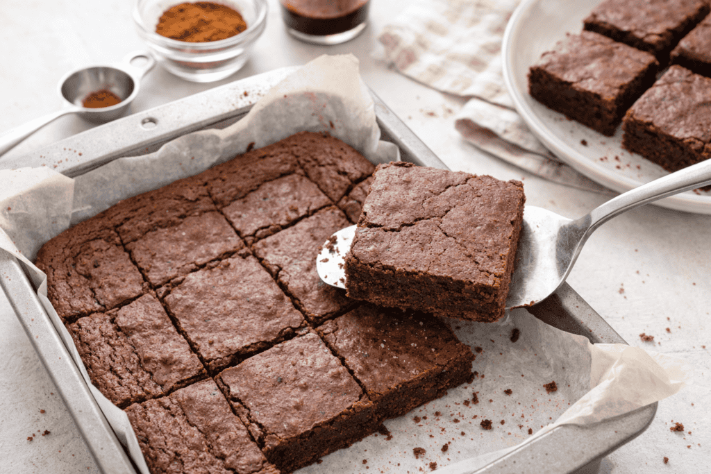 Freshly baked chocolate brownies cut into squares on a baking tray.